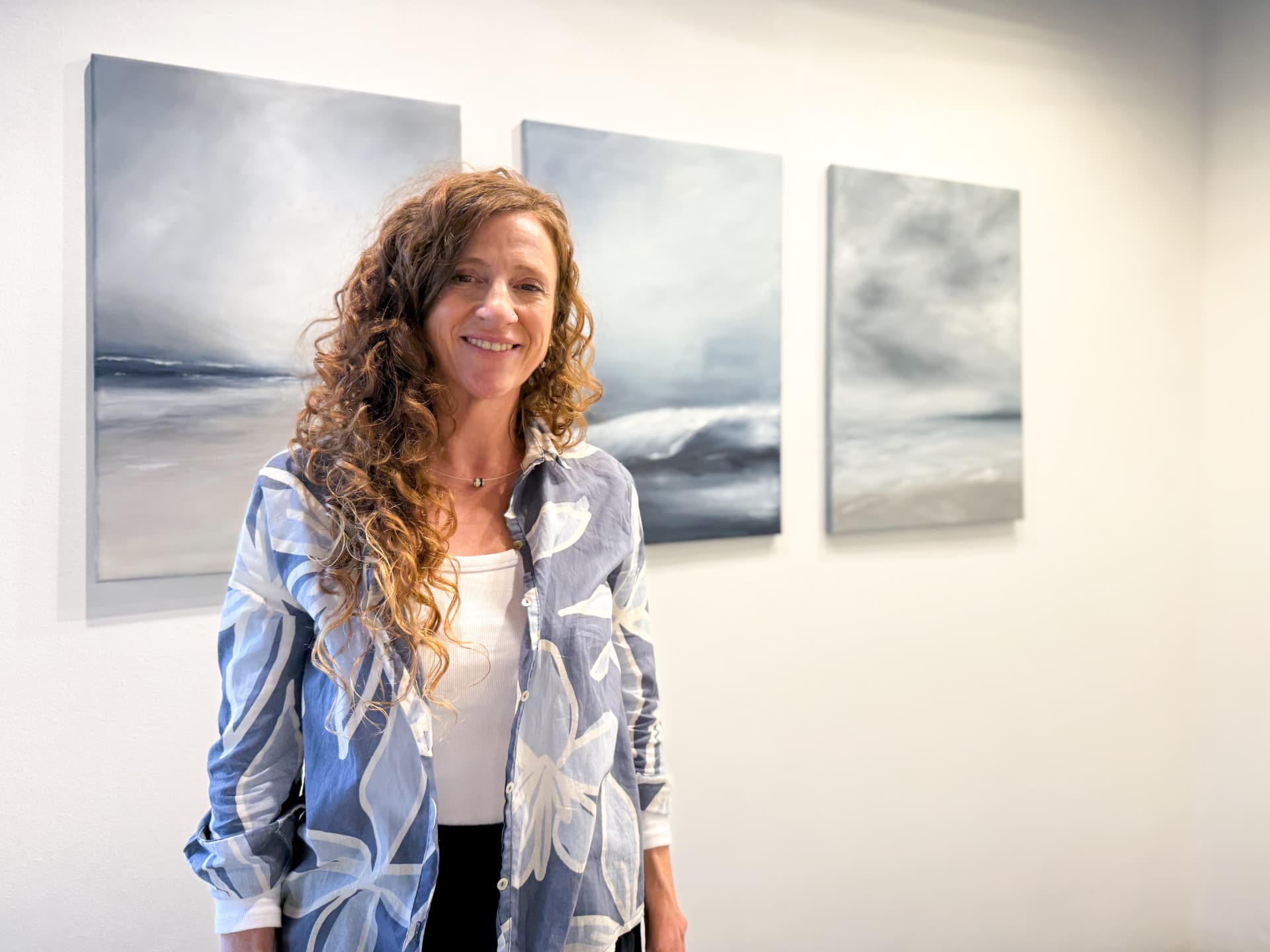 Mariana Taglioretti en la sala de exposición junto a sus pinturas